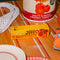 yellow 'double concentrated tomato paste' bottle opener on a table surrounded by other tomato themed items