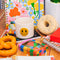 white ceramic mug with rainbow shapes handle and yellow smiley face on the front