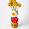 stacked vase with white flower, an apple on it's side and smiley face with flowers inside