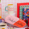 pink and red 'eraser' pencil case with cursive 'ready for anything' on the side surrounded by ban.do items