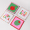 sideview of set of 4 beaded coasters: green beaded with cherry print, white with colorful beaded 'tres bien!', white with colorful beaded 'ooh lala', and pink with beaded olive.