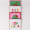 stacked set of 4 beaded coasters: green beaded with cherry print, white with colorful beaded 'tres bien!', white with colorful beaded 'ooh lala', and pink with beaded olive.