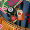 fidget keychain with gold heart photo frame, enamel orange juice charm, and 8-ball de-stress ball on a tray