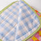 light blue and white gingham underside of colorful patchwork print quilted blanket with light green trim