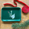 green small trinket tray with putunia holding a pine branch with red ribbon and branch next to it