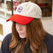 model wearing cream dad hat with red bill and embroidered snoopy and strawberry print
