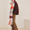 side view of model wearing thick scarf with various shades of blue and red checkers and fringe