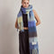 model wearing thick scarf with various shades of blue checkers and fringe