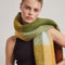 up close of model wearing thick scarf with orange, burnt red, and moss green print and fringe