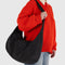up close of model wearing black large crescent bag with interior key leash