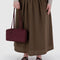 model holding mahogany rectangular nylon bowler bag with matching zipper and charm clasp