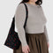 model wearing black small nylon sling bag with red painted wildflower print