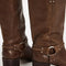 back view of model wearing tall dark brown leather boots with silver buckle and strap detail around the ankle