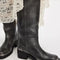 model wearing black distressed leather pull-on tall boots