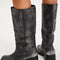 back view of model wearing black distressed leather pull-on tall boots