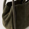 side view of dark olive suede small handbag with piped handles