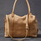back view of light tan leather purse with several zippered pockets, double handles and crossbody strap