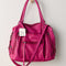hanging raspberry pink leather tote bag with several zipper pockets, double handles, and crossbody strap