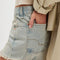 side view of model wearing light blue washed denim with moderate distressing on the hem