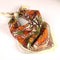 tied cream background bandana with orange, green, gold and pink with chocolate brown outlines