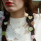 model wearing round honey brown, round matcha with carved lines, heart-shaped cream shell, and flower-shaped pastel pink.