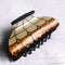 up close of white and brown geometric vintage lamp inspired hair claw