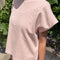 side view of model wearing baby pink relaxed fit cotton tee with muscle type sleeves and side vents
