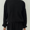 model wearing black colored waffle sweatshirt with slight balloon sleeves