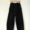 black corduroy arc pants with side panels and pockets on a hanger