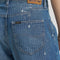 up close back view of model wearing blue cropped button jeans with white bleach splatters