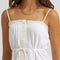 up close of model wearing white cami tank with ruffle trim, button front and tie waist