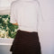 back view of model wearing white cropped relaxed fit tee with black horseshoes on the bust