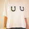 up close of model wearing white cropped relaxed fit tee with black horseshoes on the bust