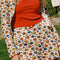model wearing white cotton mini skirt with red lettuce trim, red bow front, and retro primary color floral print