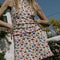 model wearing white cotton mini skirt with red lettuce trim, red bow front, and retro primary color floral print