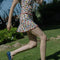 side view of model wearing white cotton mini skirt with red lettuce trim, red bow front, and retro primary color floral print