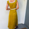 back view of model wearing chartreuse midi dress with white lace accents on the bust, two tie front and ruffle detail on the shoulders