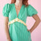 up close of model wearing green puff sleeve v-neck midi dress with pale yellow ruffle under the bust