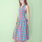 model wearing colorful plaid midi dress with button front, collar detail, and drop waist