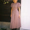 model wearing brown striped midi dress with puff sleeves, v-waistline and tie back