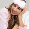 model wearing pale pink and white stripe weighted eye mask around their head