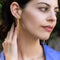 model wearing gold star earrings with gold chains coming from the back