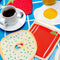 set of 4 brunch linen napkins: bloody mary, strawberry, egg, and bagel with cream cheese in a table setting