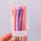 model holding set of 4 pink and purple gel pens with book themed saying on the side