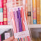 model holding set of 4 pink and purple gel pens with book themed saying on the side