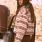 back view of model wearing cropped white zip up jacket with brown alpine print