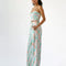 side view of model wearing pastel wavy print bottoms with button closure and flared legs and matching bustier top