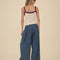back view of model wearing dark blue denim wide leg pants with drawstring waist, elastic waist and raw hems