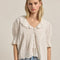model wearing ivory blouse with embroidered collar and hem, button front and pin-tucked details