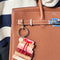 colorful book stack bag charm with gold hardware on a brown bag